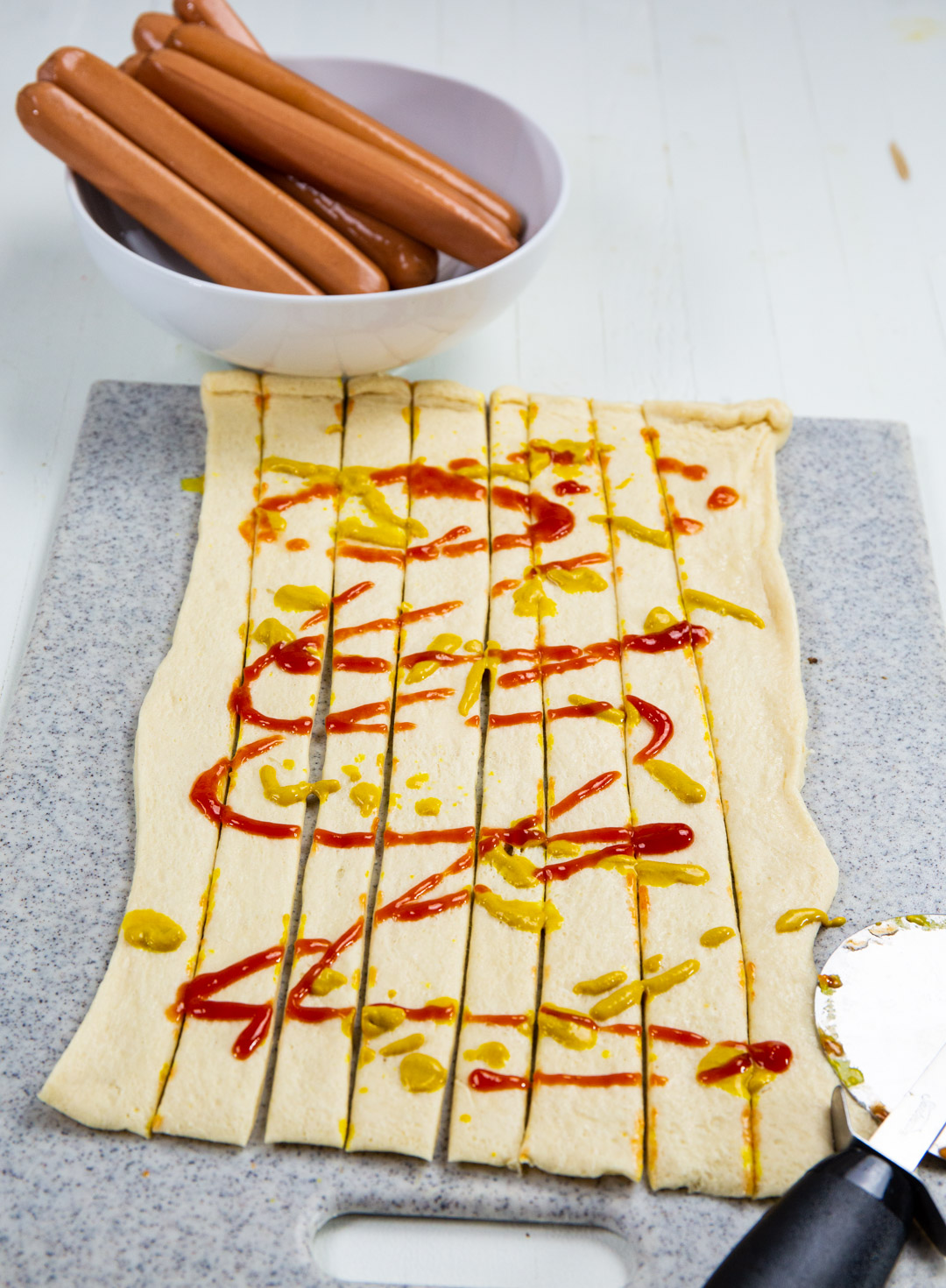 Ketchup and mustard spread on crescent dough.