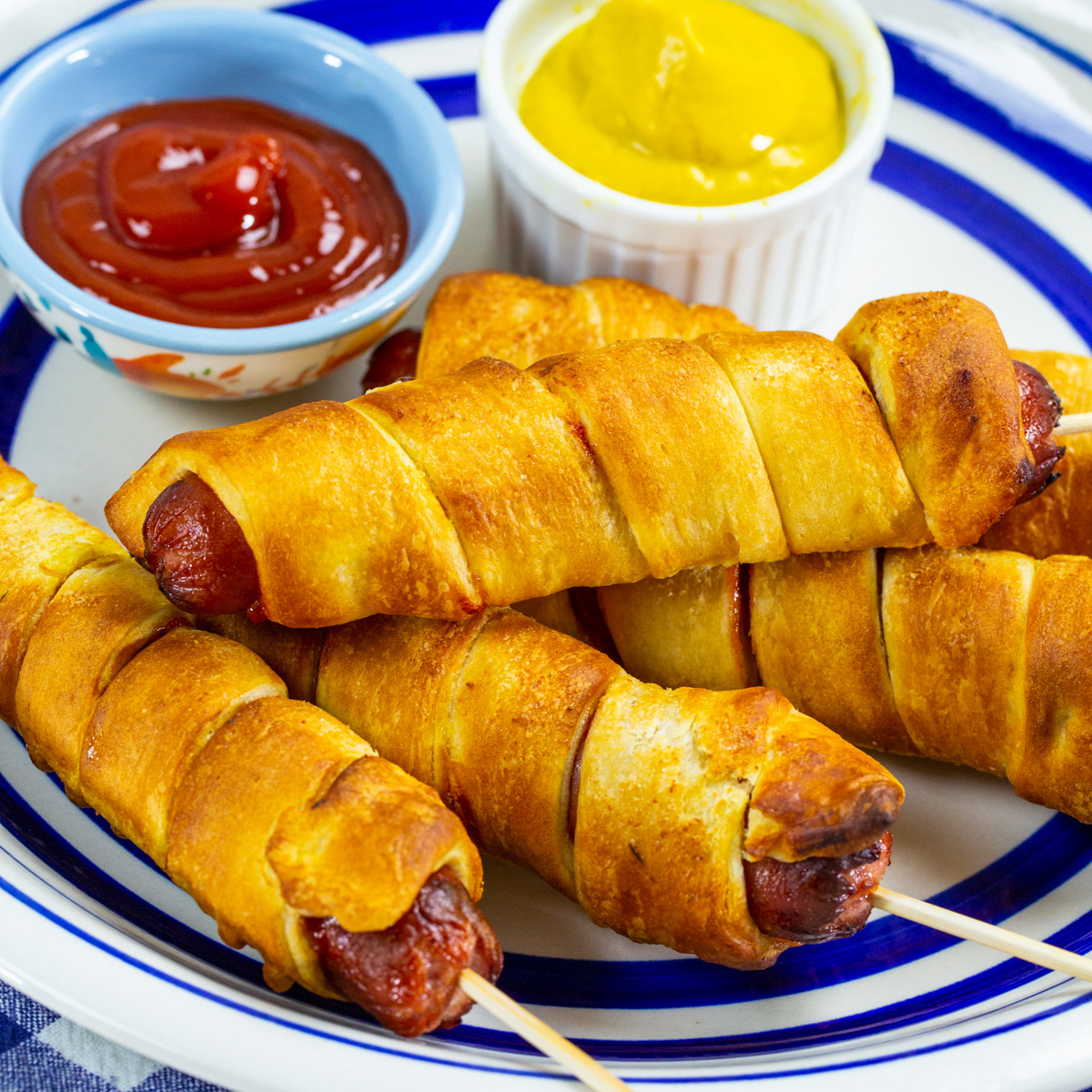 Air Fryer Crescent Wrapped Hot Dogs on a plate with ketchup and mustard.