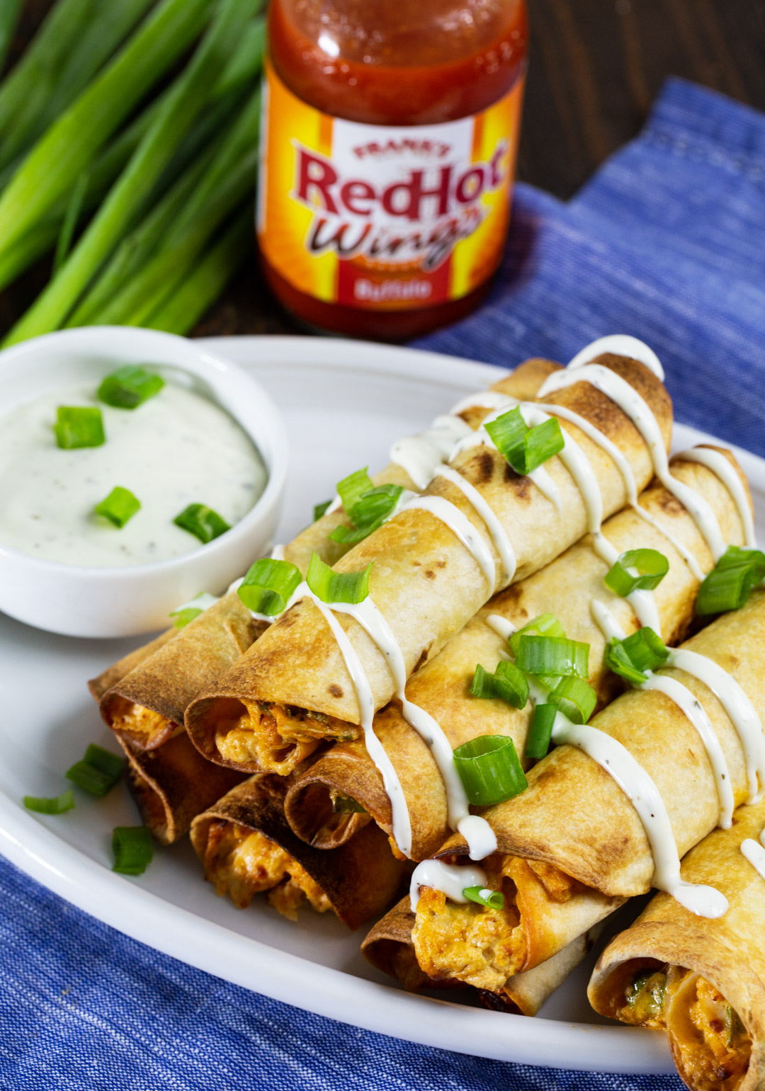 Buffalo Chicken Taquitos on a plate with ranch dressing.