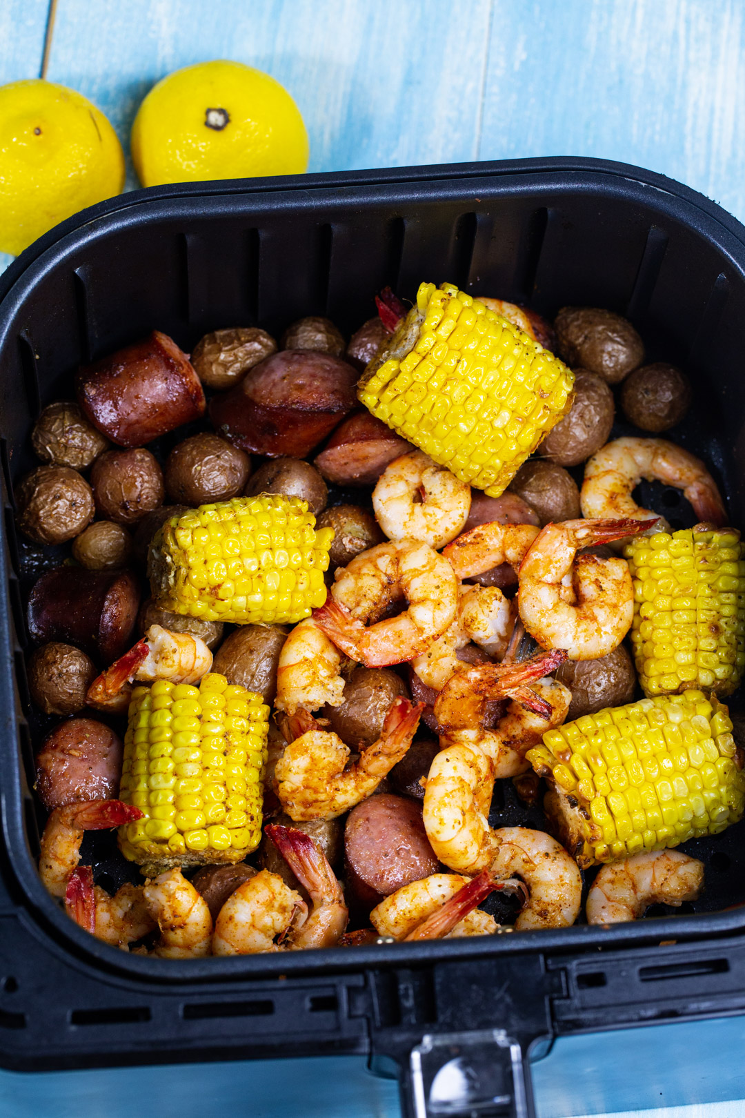 Shrimp, corn sausage and potatoes in air fryer basket.