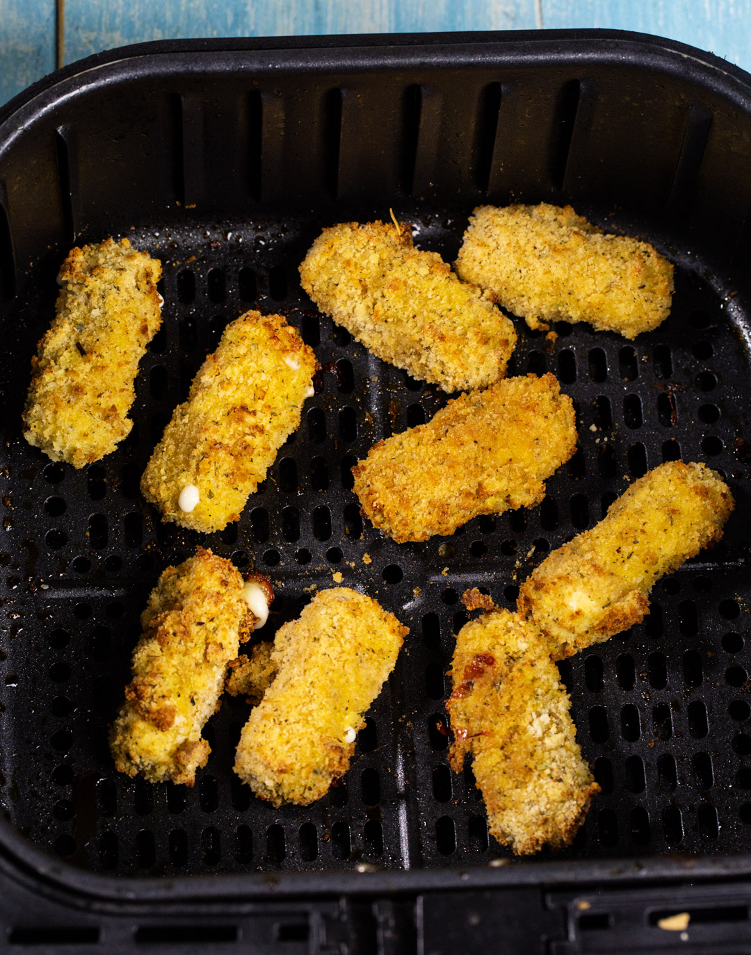 Mozzarella sticks in air fryer basket.
