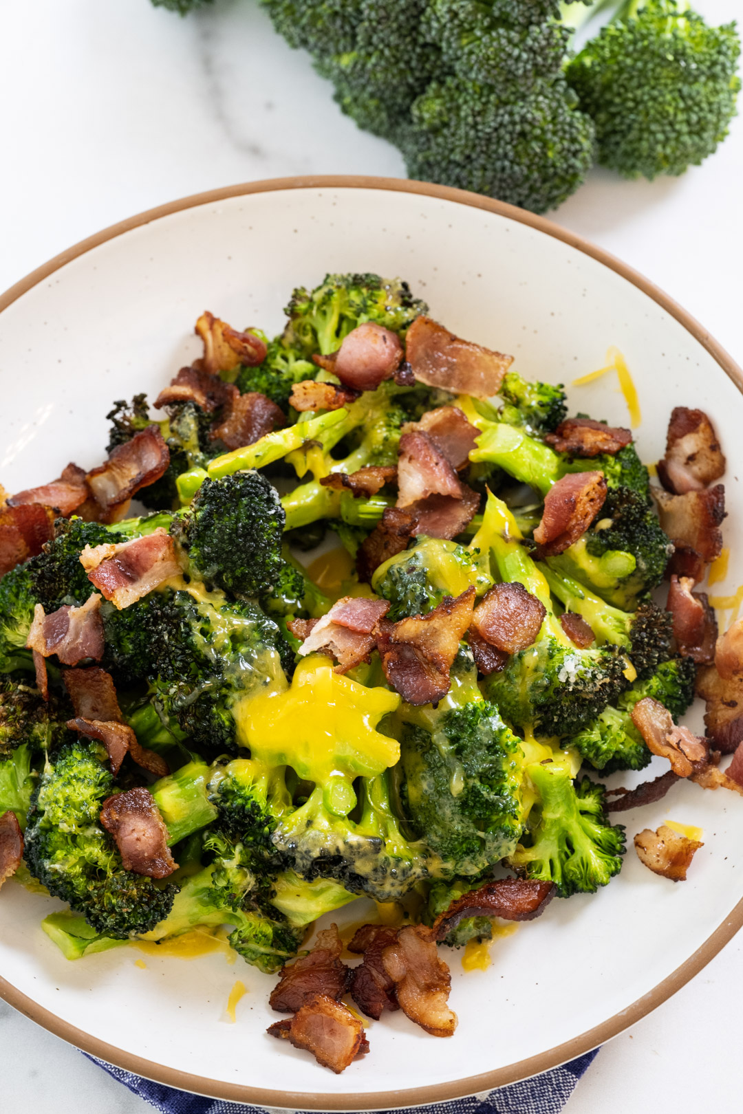 Broccoli topped with cheese and bacon in a bowl.