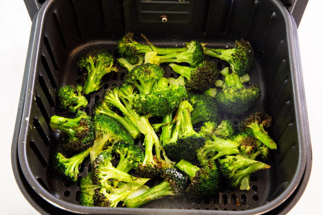 Cooked broccoli in air fryer basket.