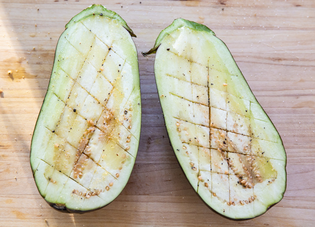 Eggplant cut in half and scored with a knife.