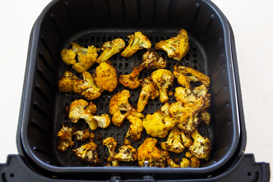 Cauliflower in air fryer basket.