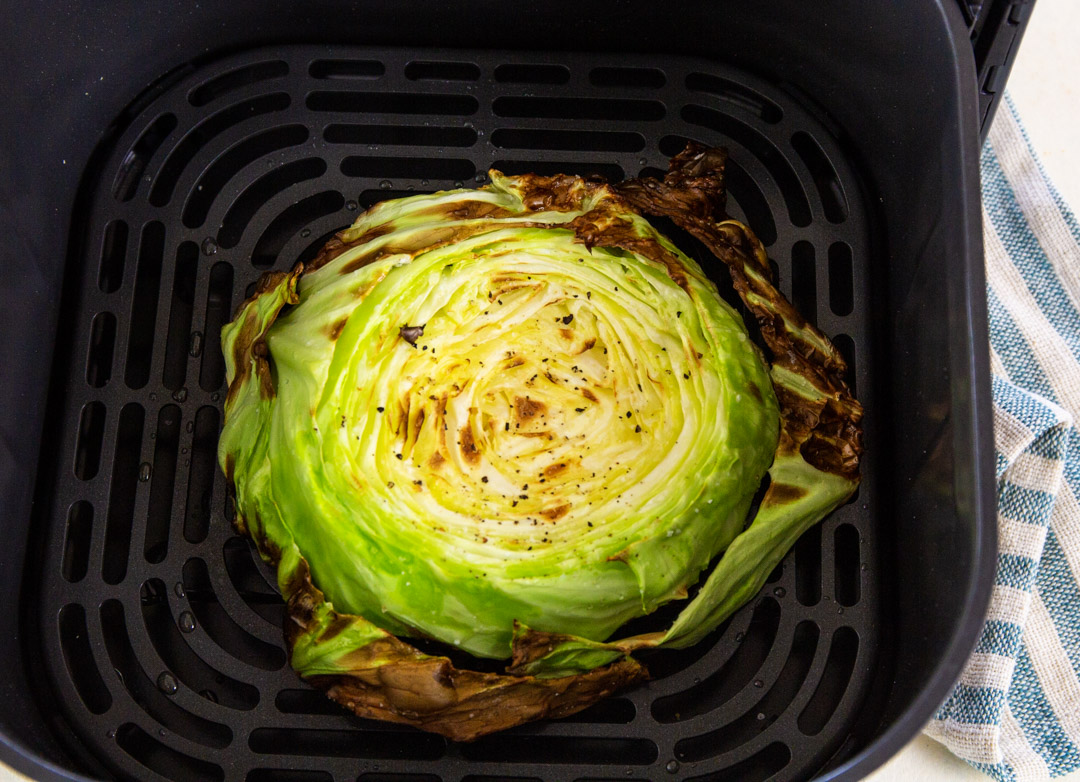 Cooked cabbage steak in air fryer basket.