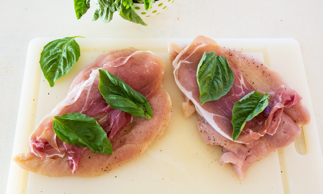Chicken topped with prosciutto and basil.