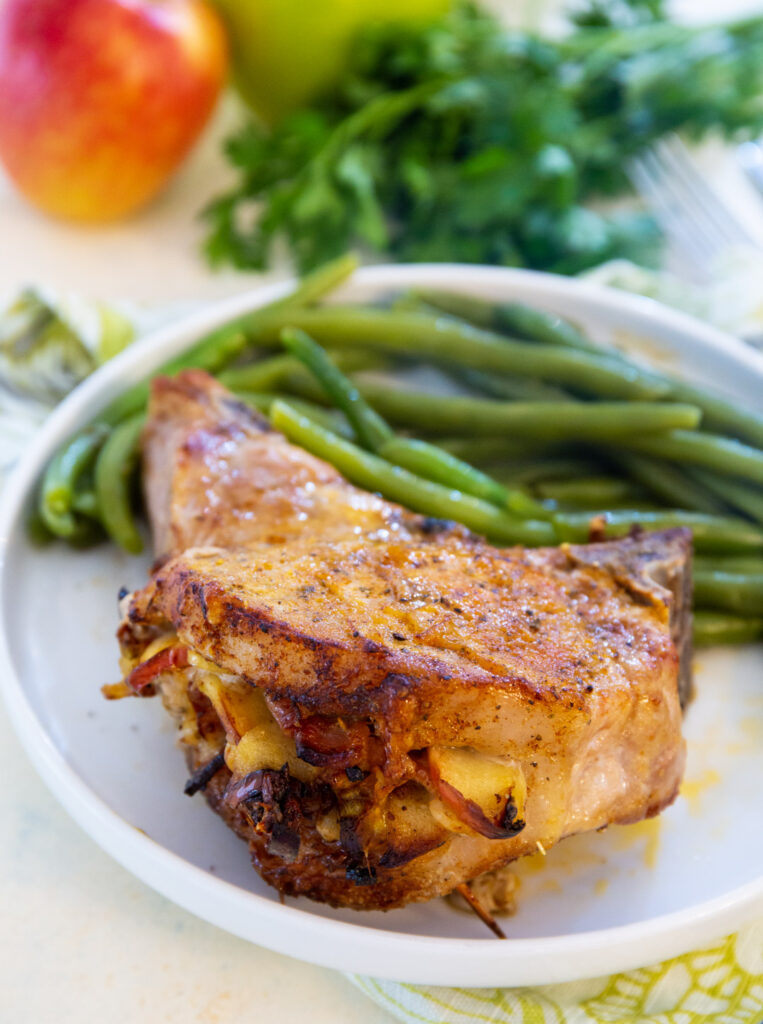 Stuffed pork chops on a plate with green beans.